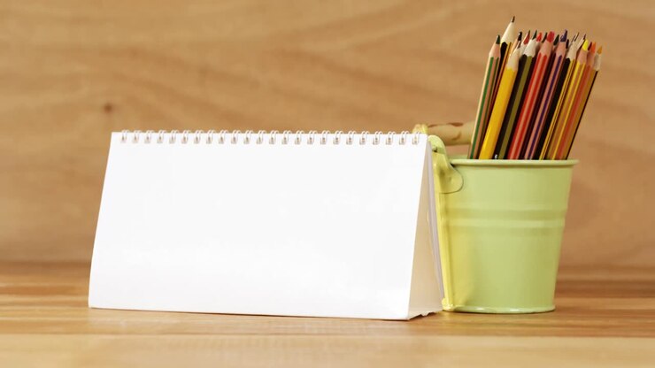 Close-up of blank spiral calendar with colored pencil