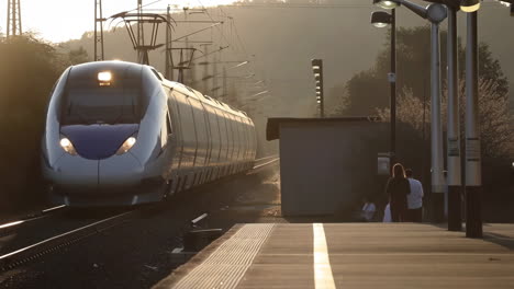 high-speed train arriving at a station platform during golden hour