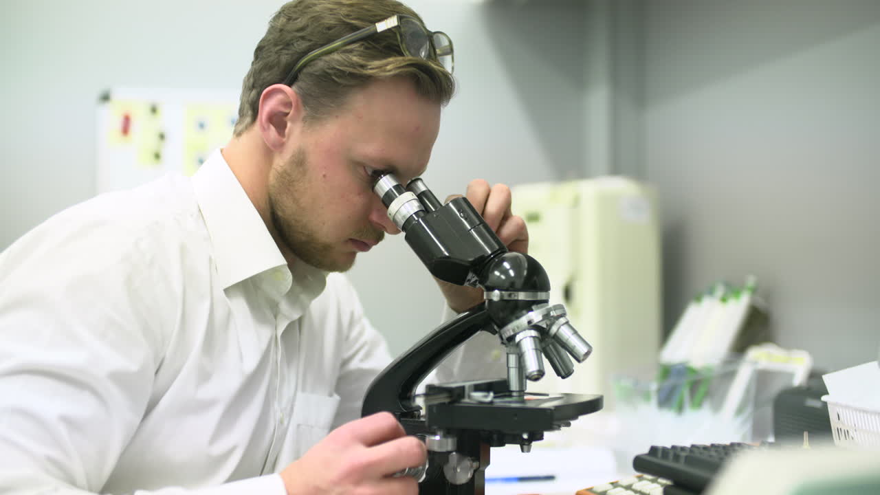 Man Looking Through Microscope in a Laboratory