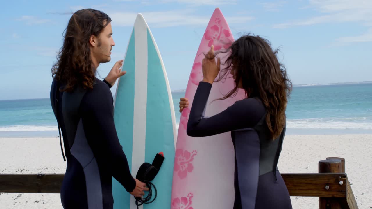 pareja de pie en una pasarela de madera con tabla de surf 4k