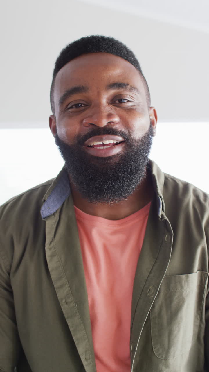 Vertical video portrait of happy african american man at home laughing to camera, in slow motion