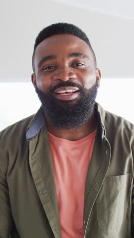 vertical video portrait of happy african american man at home laughing to camera, in slow motion