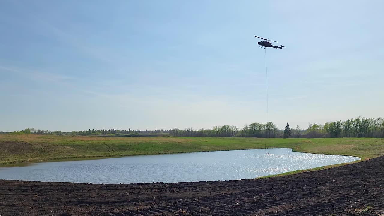 캐나다 앨버타 의 산불 때 인근 호수 에서 물 을 모으는 헬리 ⁇ 터 버 ⁇