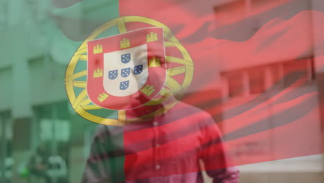 animation of flag of portugal waving over african american man wearing face mask in city street