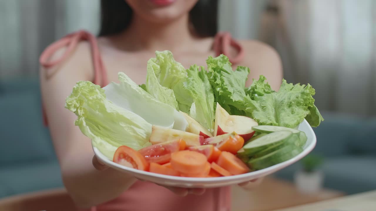 집에 앉아있는 동안 건강한 음식의 접시를 카메라에 보여주고 있는 여성의 손의 근접
