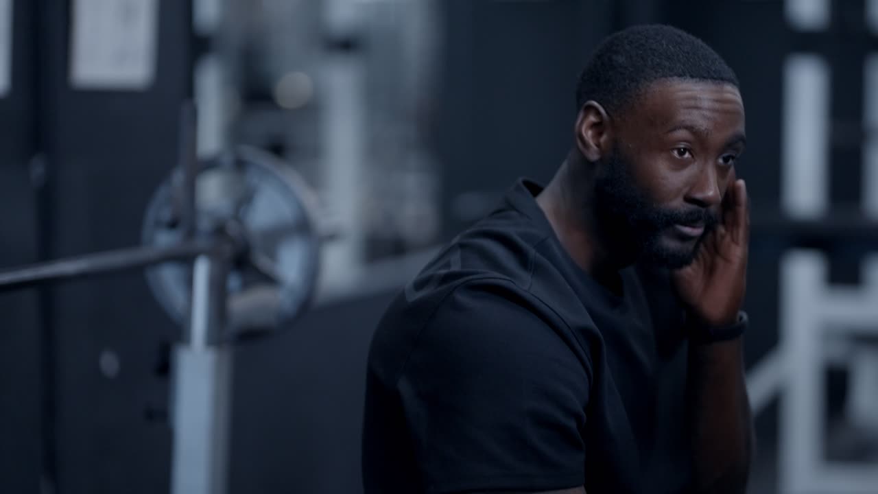 Un uomo afroamericano che si riposa tra una serie e l'altra in palestra