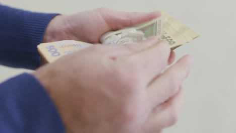 a man counts ukrainian money for 500 uah