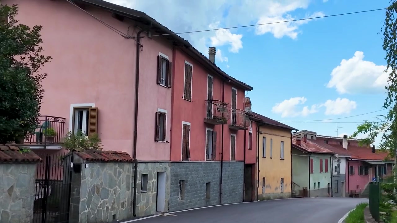 Un fluido movimento di telecamera percorre una strada curva, oltrepassando ville storiche e muri in pietra.