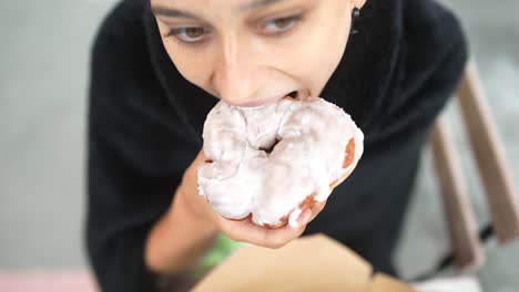 una mujer comiendo una rosquilla esmaltada.