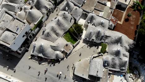 Slow-drone-360°-panoramic-view-of-Alberobello-above-the-main-street-full-of-typical-trulli