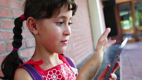 escolar que usa una tableta digital en el pasillo de la escuela
