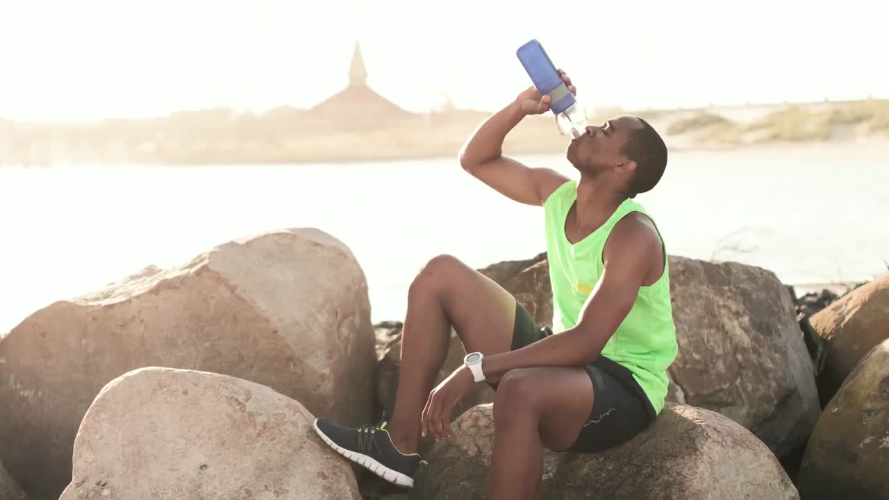 hombre bebiendo agua en la playa