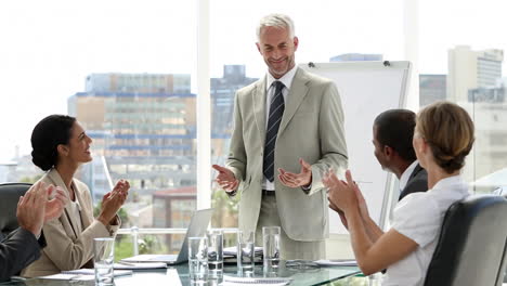 businessman presenting to his team who applaud him