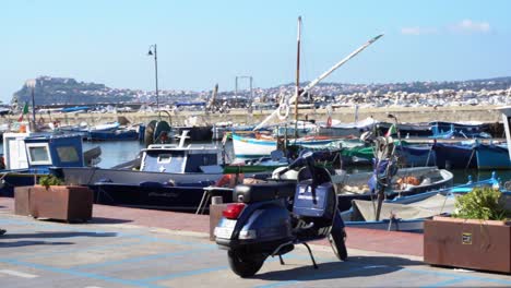 Pan-shot-of-motor-boats-docked-along-seaside-in-Procida,-Marina-Corricella,-Italy-on-a-sunny-day