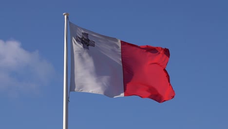 waiving malta flag in slow motion on clear blue sky - static shot