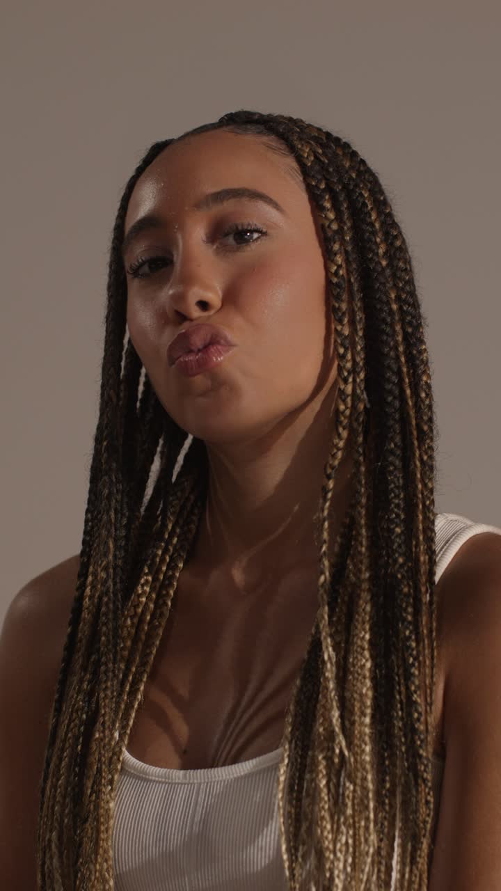 смеющаяся молодая женщина надевает блеск на губы и вдыхает поцелуй в камеру 1