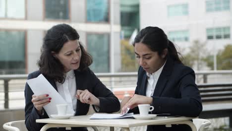 Focused-businesswomen-with-papers-in-cafe