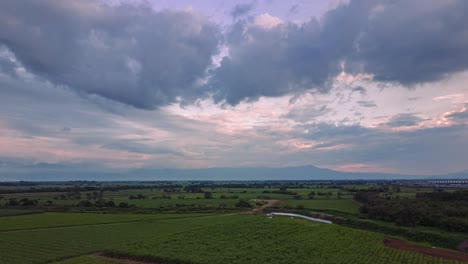 Hyperlapse-Aus-Der-Luft,-Der-Bei-Sonnenuntergang-über-Einem-Frischen-Zuckerrohrfeld-Mit-Dramatischen-Wolken-Fliegt