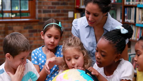 Pupils-looking-at-the-globe-in-library-with-their-teacher