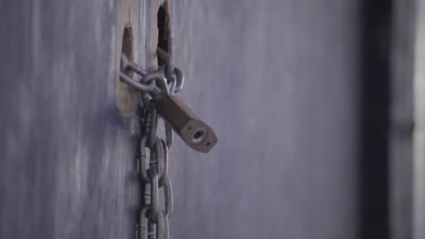 close up of lock and chain, locking a old ugly wooden door