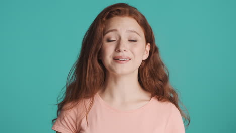 Redheaded-girl-in-front-of-camera-on-turquoise-background.