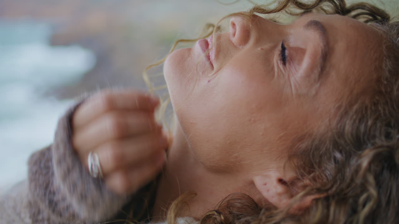 retrato viajero sereno mirando la cámara en la costa del océano ventoso. mujer posando mar