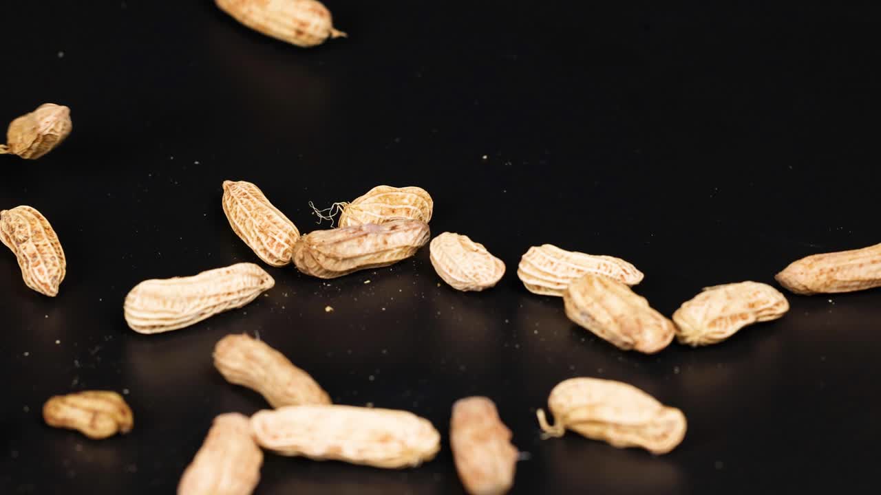 Peanøtter som beveger seg dynamisk over en svart bakgrunn