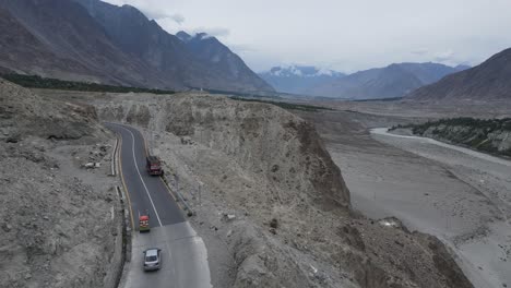 vista aérea del paso de montaña babusar, pakistán, tráfico en la ruta escénica, colinas rocosas y picos nevados