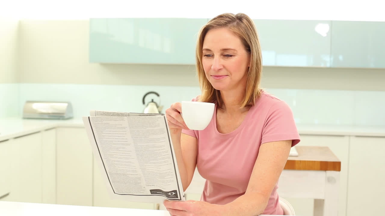 Donna matura che beve caffè leggendo il giornale