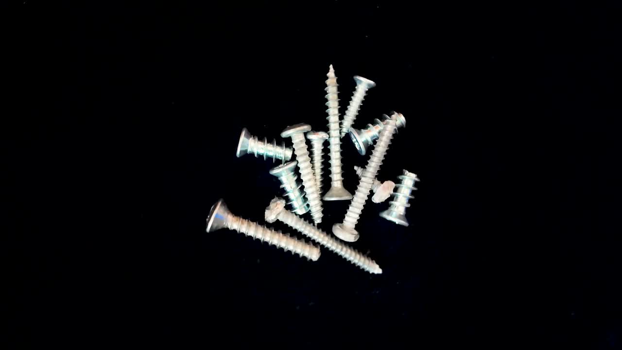 Metal screws rotating in synchronization against a black backdrop, industrial design, clean black background