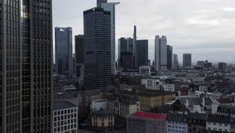 modern tall skyscrapers in business district contracting with historic town development. fly above city at cloudy day. frankfurt am main, germany