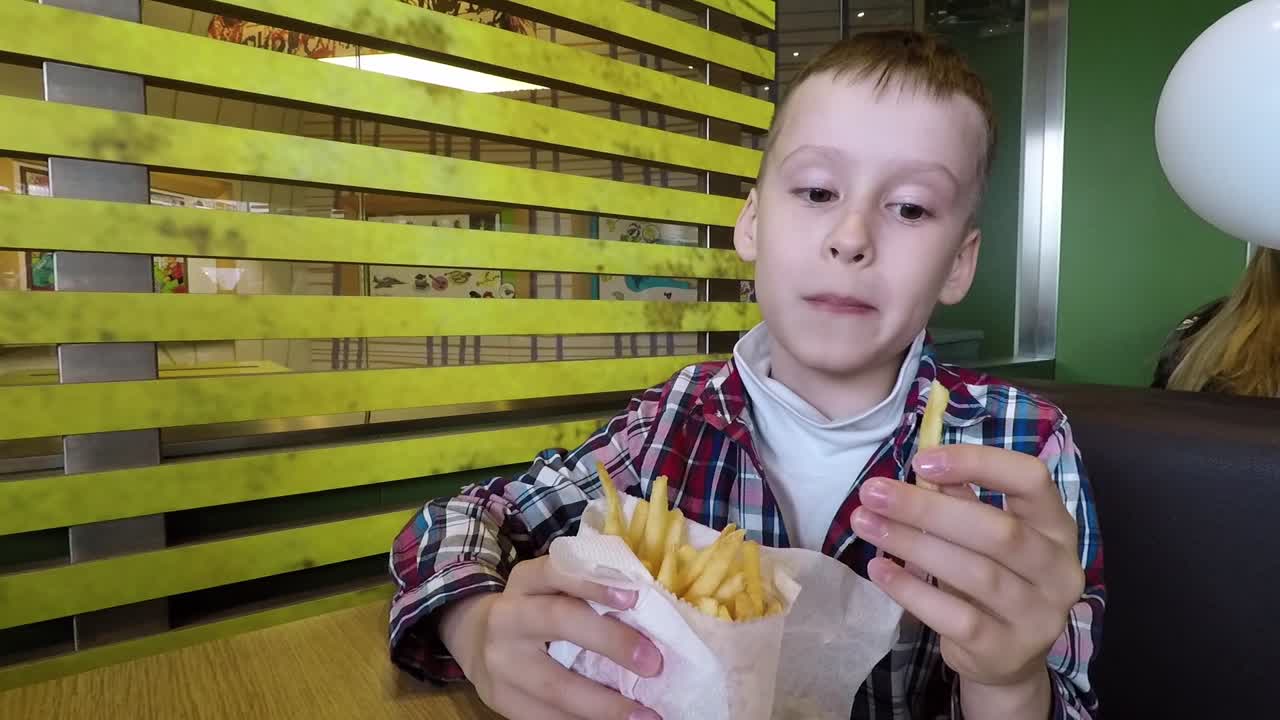 Bambino che mangia patatine fritte. Bambino che si gusta le patatine fritte al bar