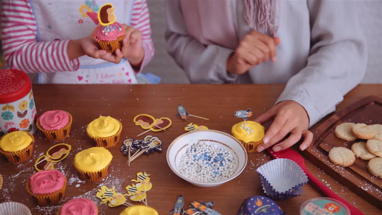 Mother and child decorating cupcakes. Static shot.