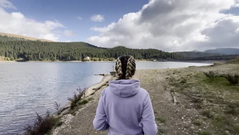 Mujer-Solitaria-Caminando-Cerca-De-La-Orilla-Del-Lago-De-Bolboci-En-Las-Montañas-De-Bucegi,-Rumania