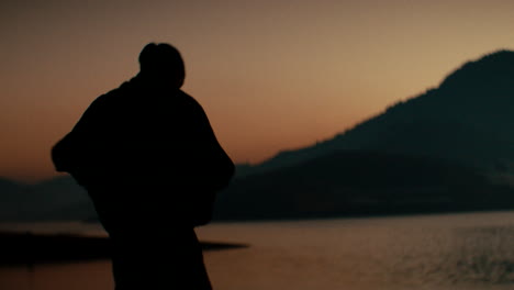 silhouette of person at sunset by the lake
