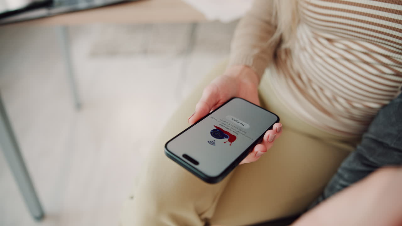 mujer sentada sosteniendo un teléfono inteligente en sus manos