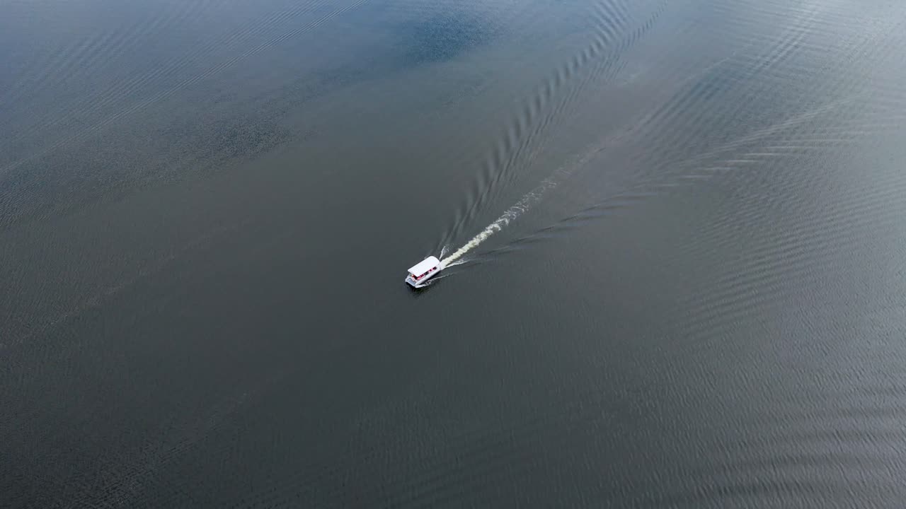 Drone close-up at midday of a boat leaving water ripples during a tour on Presa Calles, San José de Gracia, Aguascalientes, Mexico. Scenic Pueblo Mágico landscape and aquatic travel footage