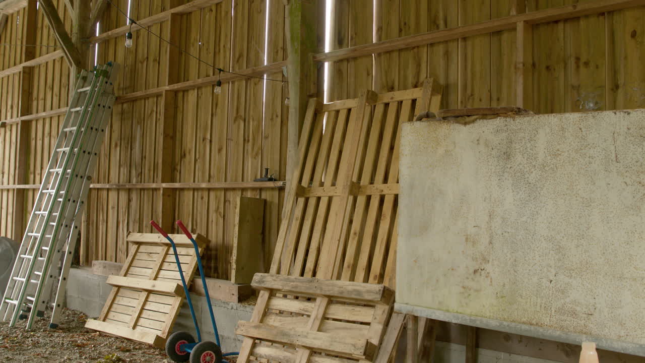 Scale e pallet conservati in un fienile in legno. Panoramica a sinistra, a mano libera.