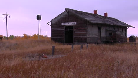 an old station house sits in a field near a railroad track 1