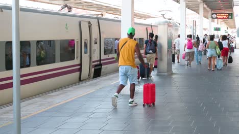 people boarding a train at a busy railway station