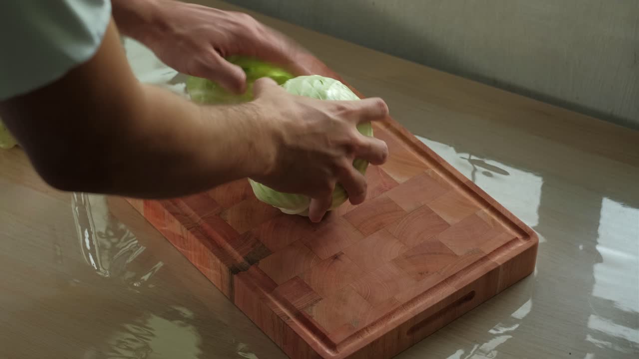 Hands preparing and peeling cabbage for slicing on wooden chopping board - medium static shot