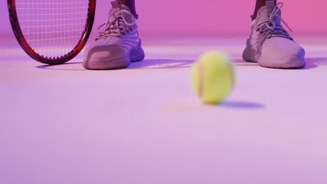 Video-of-feet-of-african-american-male-tennis-player-bouncing-ball-in-neon-pink-lightning