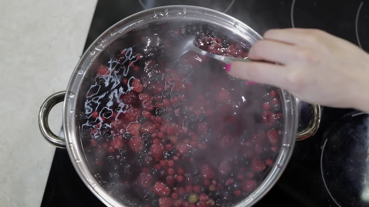Stir the berries in pot with boiling water. Cooking compote. Kitchen