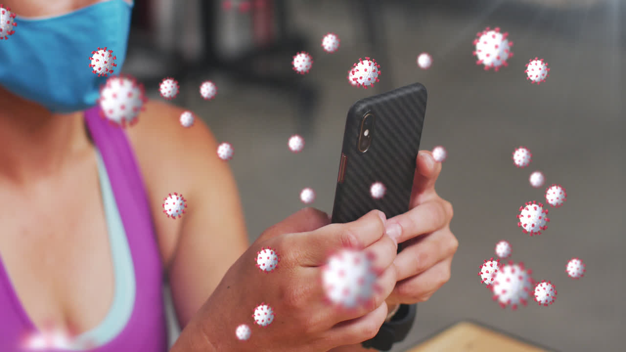 múltiples células de covid-19 flotando contra una mujer caucásica en forma que usa una máscara usando un teléfono inteligente