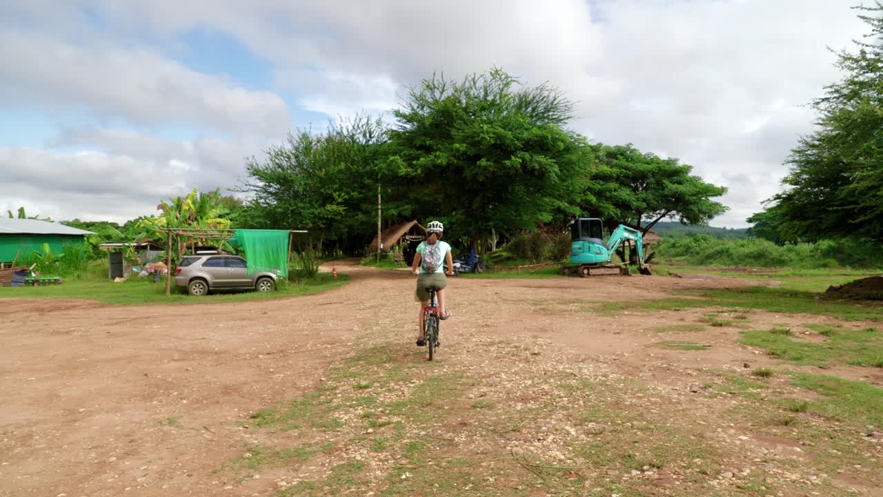 식료품 가방과 함께 태국 시골에서 집을 향해 자전거를 타는 아시아 여성