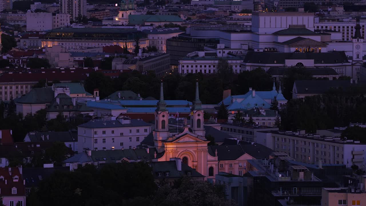 Aerial view of Warsaw city at blue hour. Church of Our Lady Queen in center of old town in the evening. Wide shot zoom. Dusk scene after sunset. Historic old town buildings. Poland,Europe