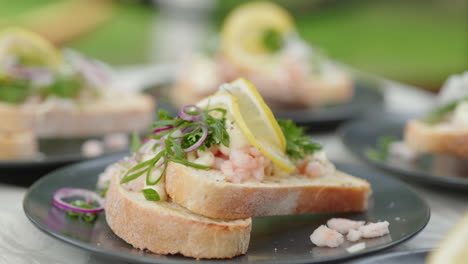 Mano-De-Una-Mujer-Exprimiendo-Un-Limón-Sobre-Sándwiches-Tradicionales-De-Camarones-Daneses-En-Platos---Cámara-Lenta