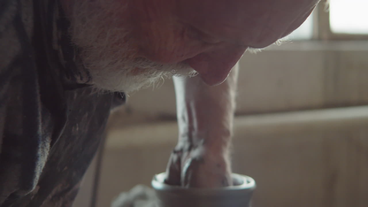 alfarero sénior haciendo jarrón de cerámica en rueda en el taller