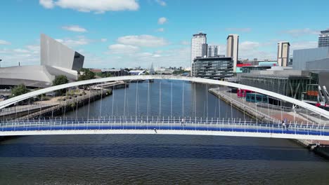 aerial drone flight along media city at salford quays flying away from the footbridge over the ship canal showing media city and the imperial war museum