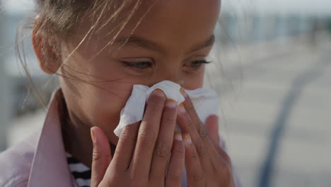 close up little girl blowing her nose using tissue young mixed race child flu outdoors